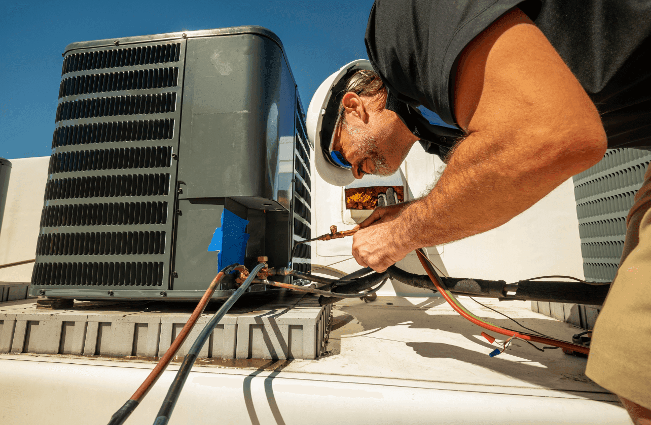 RSK Technical engineer repairing and servicing rooftop HVAC packaged unit on commercial building rooftop Dubai UAE